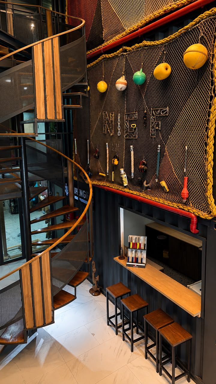 Espace d'accueil du Groupe NGF, escalier hélicoïdal et mur décoré de filets, bouées et gréement